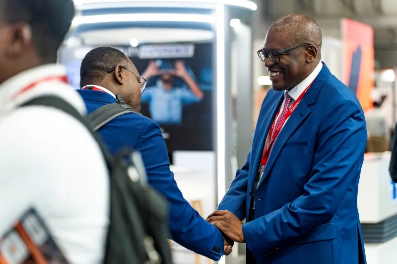 Two mining industry delegates shaking hands on the exhibition floor at Mining Indaba
